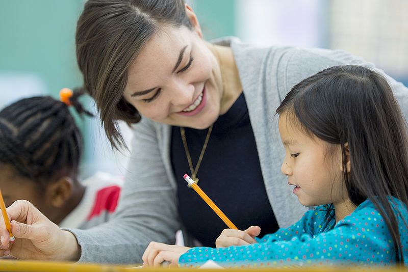 Eine Lehrerin erklärt Grundschulkindern die Aufgabenstellung 